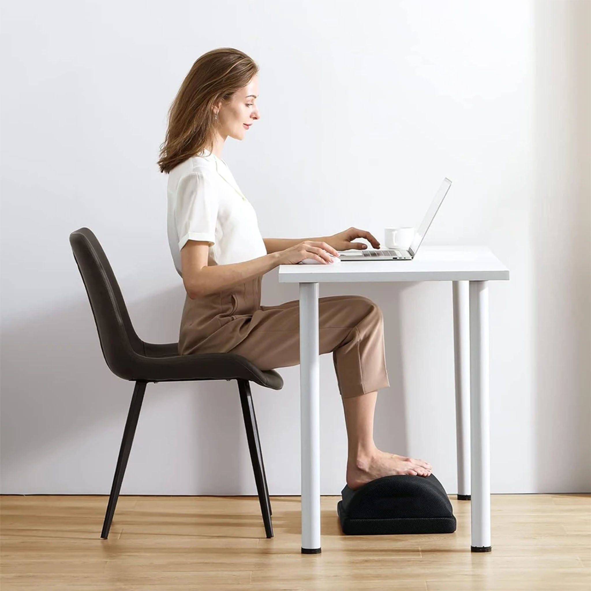Donna seduta alla scrivania, piedi su un poggiapiedi ergonomico.