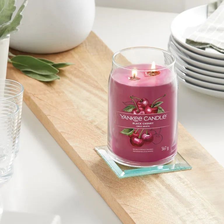 Candela profumata su tagliere. Decorazione ciliegia e scritta. Due stoppini. Su sottobicchiere.