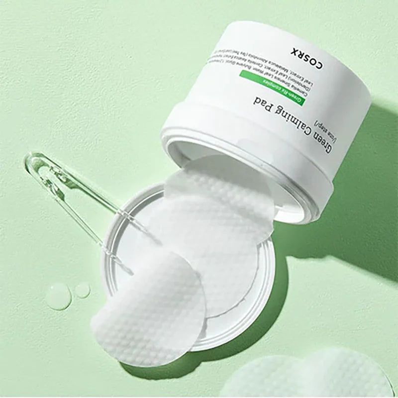 Contenitore bianco aperto con tamponi che cadono. Scritta: Green Calming Pad, COSRX. Sfondo verde.