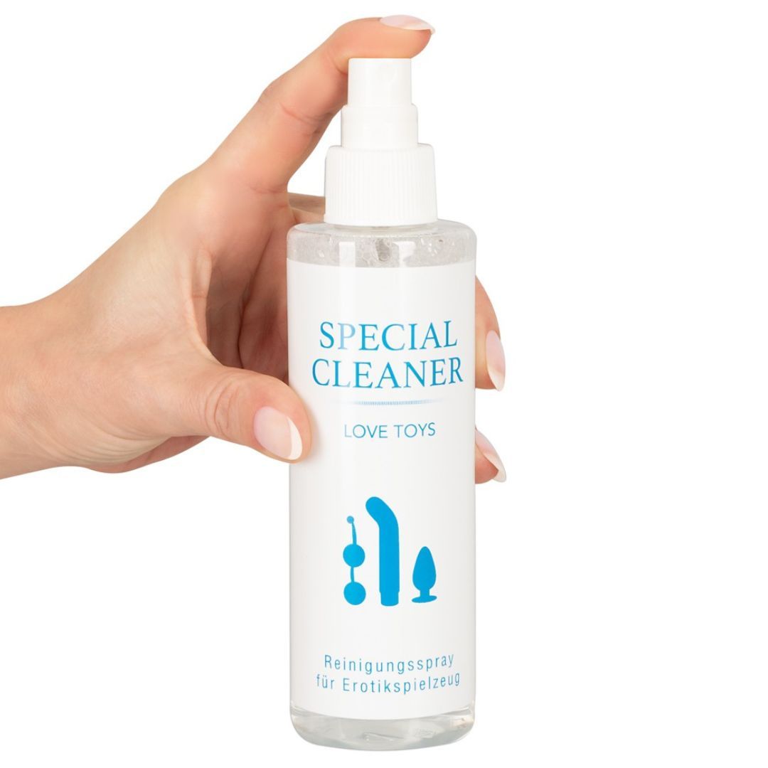 Flacone trasparente con erogatore bianco, tenuto in mano. Scritta: SPECIAL CLEANER LOVE TOYS. Spray detergente.