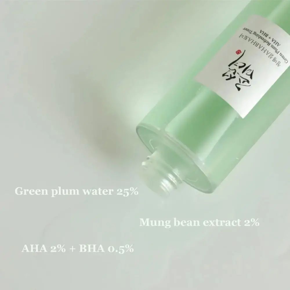 Flacone di toner, in diagonale dal basso. Testo: Acqua di prugna verde 25%, Estratto di fagioli mungo 2%, AHA 2% + BHA 0,5%.