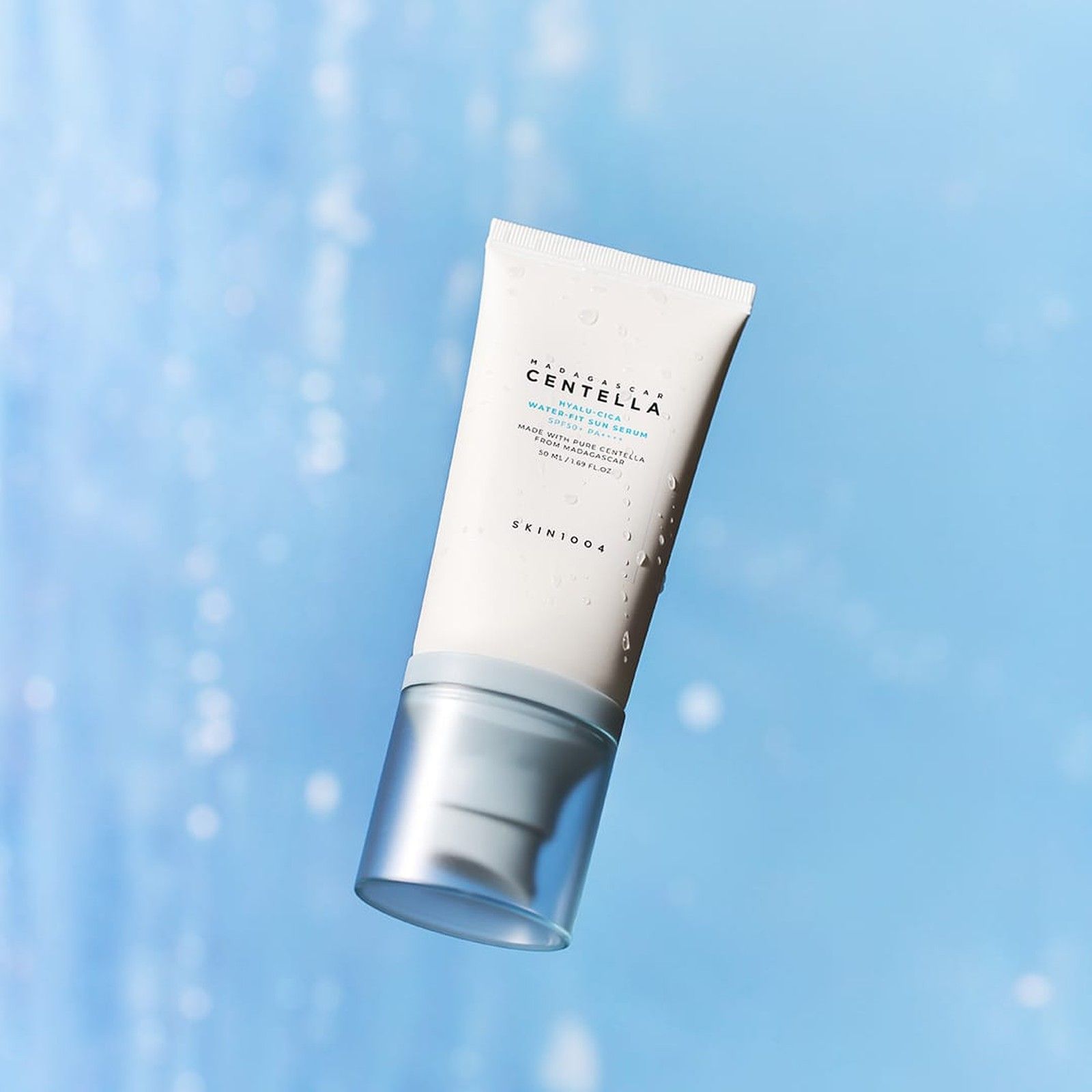 SKIN1004 Hyalu-Cica Water-Fit Siero Solare SPF 50+ PA++++ fluttua su uno sfondo blu sfocato.