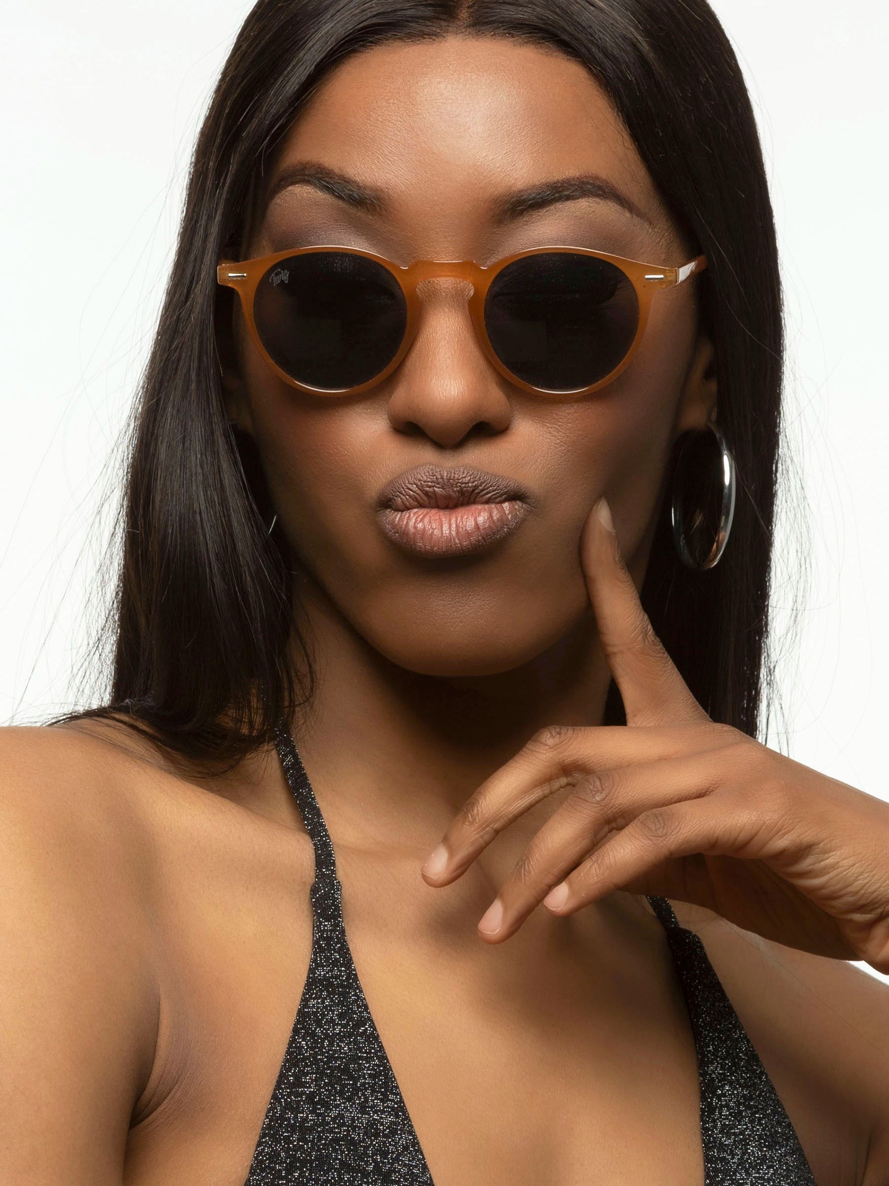 Donna con occhiali da sole marroni e lenti scure. Primo piano.