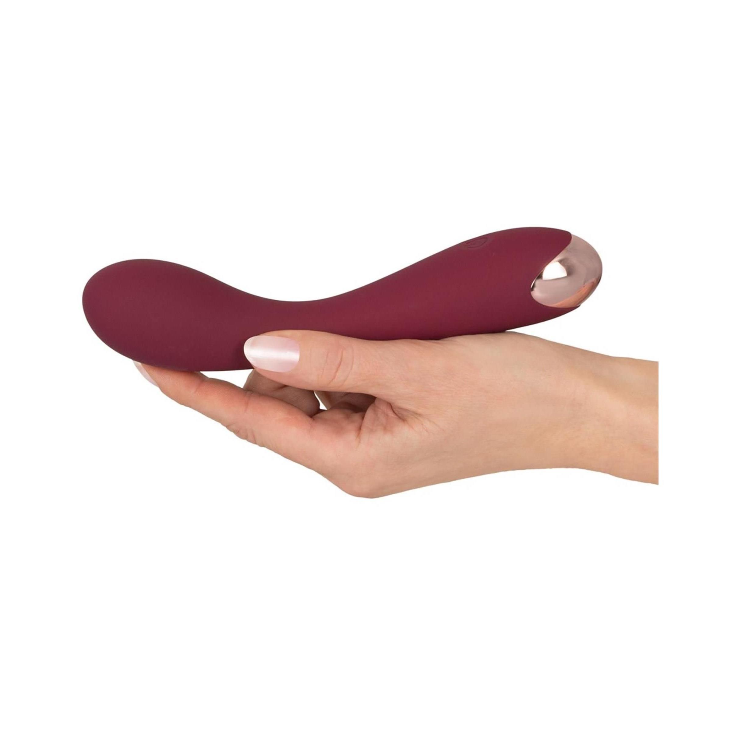 Vibratore bordeaux tenuto in mano. Punta metallica visibile.