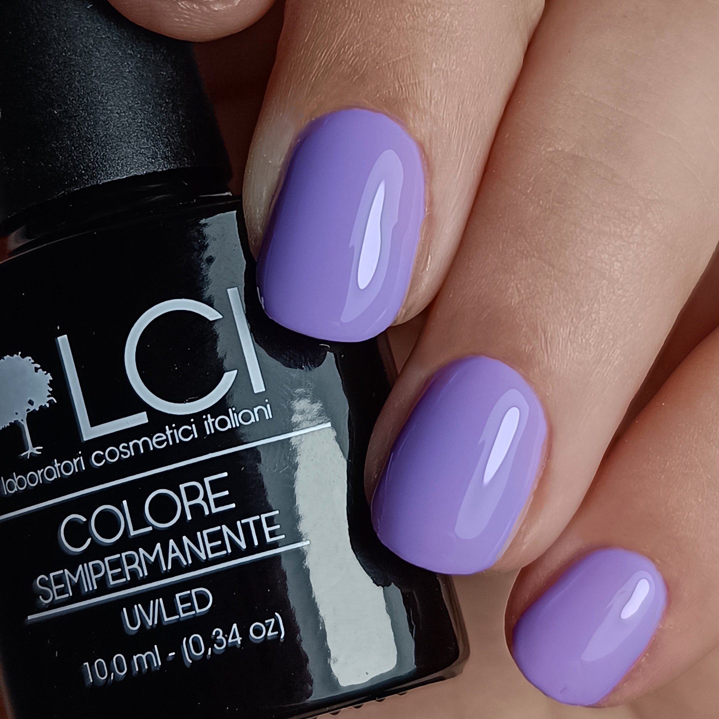 Flacone di smalto accanto a unghie laccate viola. Scritta: LCI, Colore Semipermanente, UV/LED.