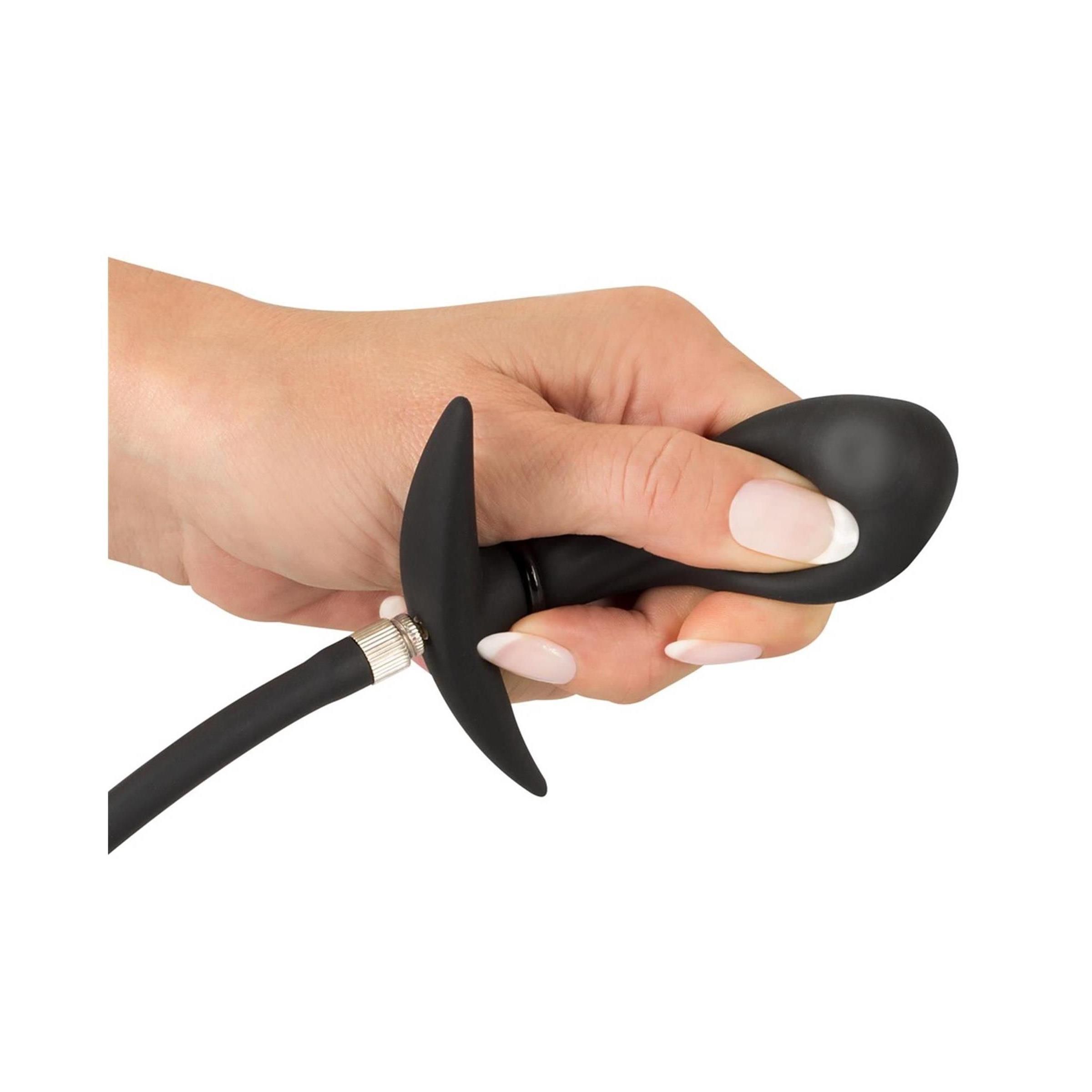 Mano che tiene un plug gonfiabile nero. Impugnatura a T e attacco del tubo visibili.