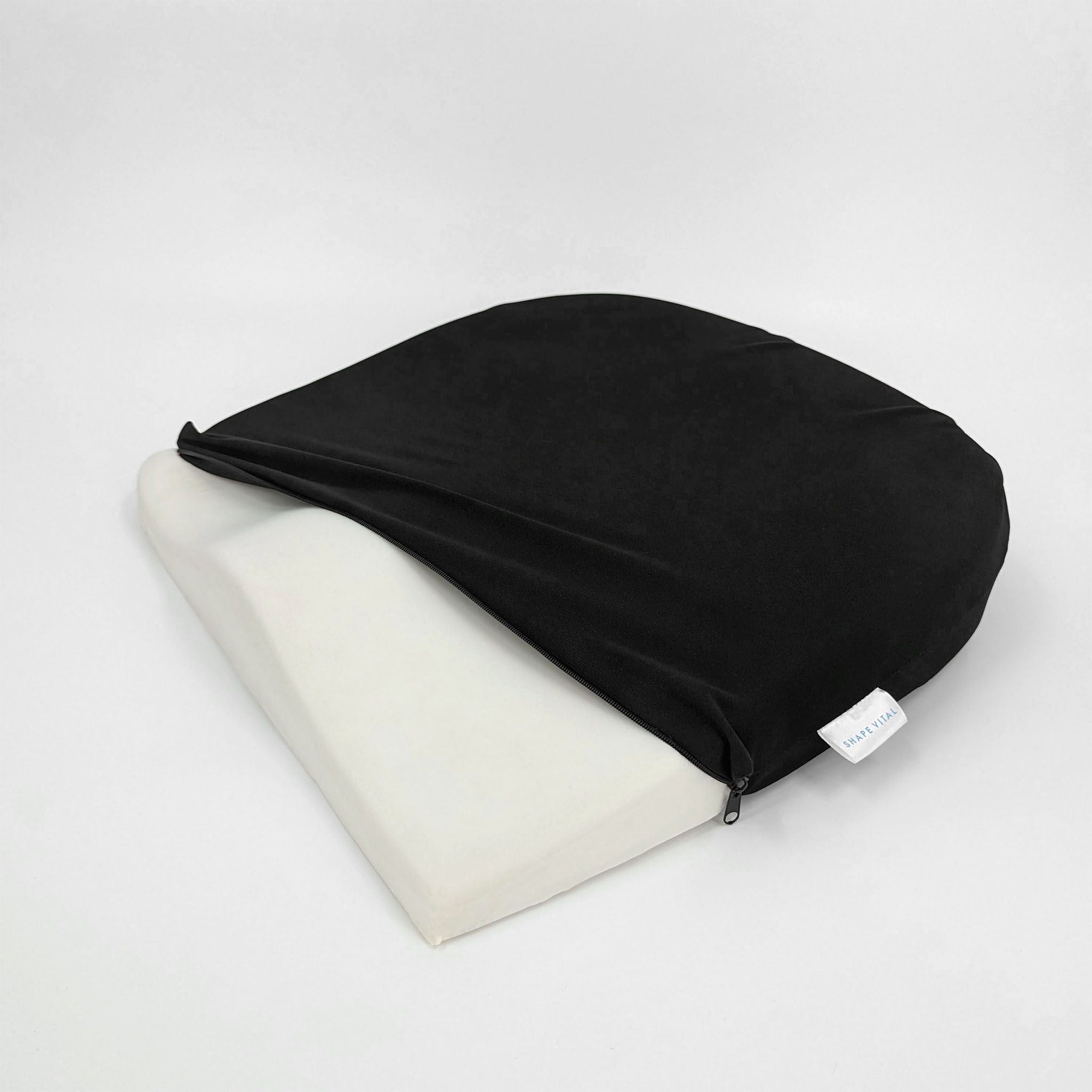 Cuscino per seduta a forma di cuneo, rivestimento nero aperto. Nucleo in schiuma visibile. Cerniera.