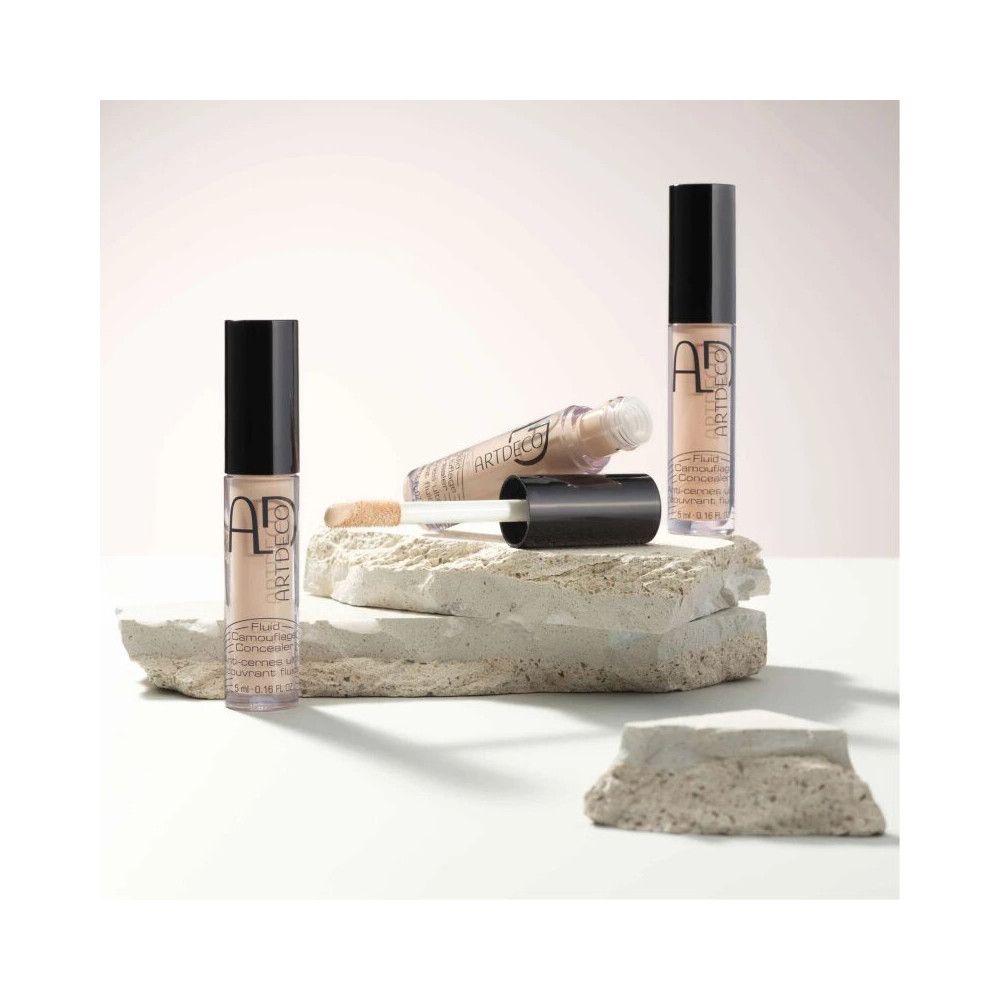 ARTDECO Concealer Fluid Camouflage, flaconi e applicatore disposti su pietre.