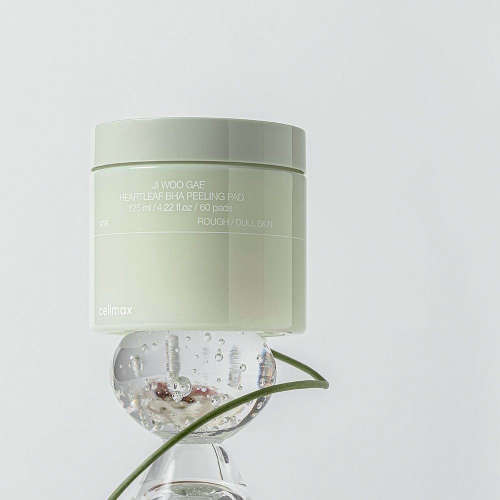 Un contenitore di Celimax Heartleaf BHA Peeling Pads posizionato su una sfera di vetro.