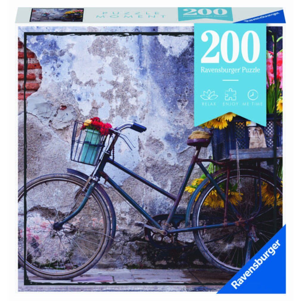 Puzzle da 200 pezzi. Soggetto: bicicletta con fiori davanti a un muro. Marca: Ravensburger. Confezione: quadrata.