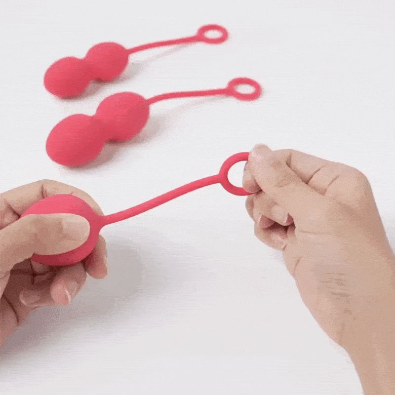 Tre sfere rosa con anelli. Una sfera è tenuta in mano.