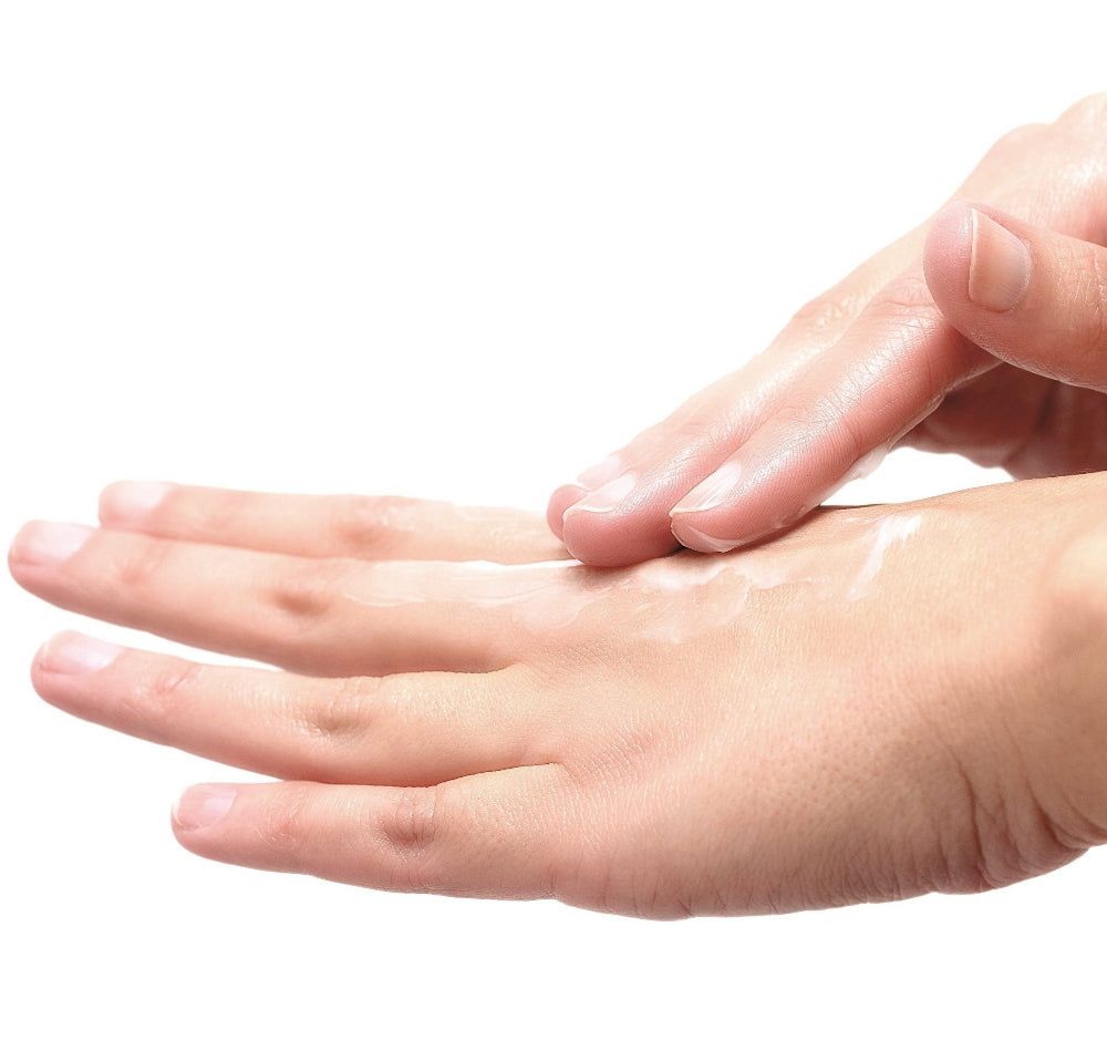 Mani, un palmo con crema, un'altra mano che distribuisce la crema. Colore della pelle, sfondo bianco.