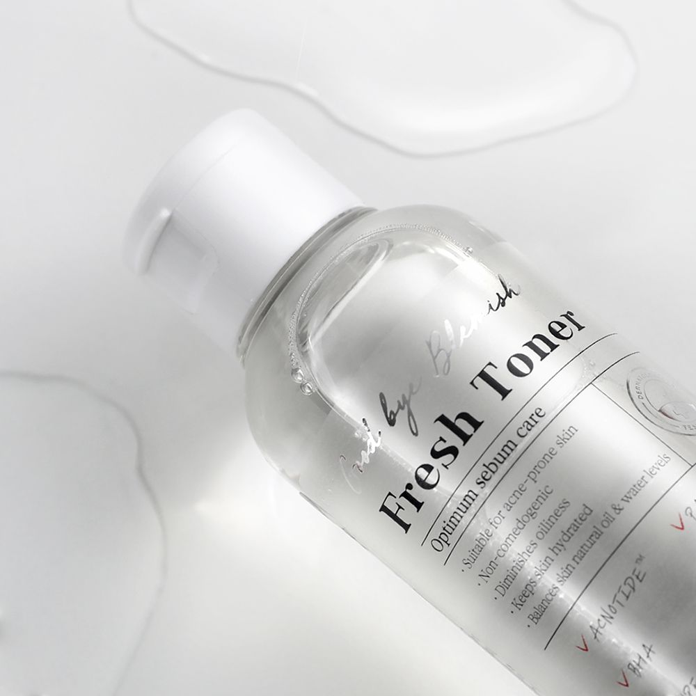 Flacone trasparente con tappo bianco. Scritta: Fresh Toner. Liquido su sfondo bianco. Contiene ingredienti.