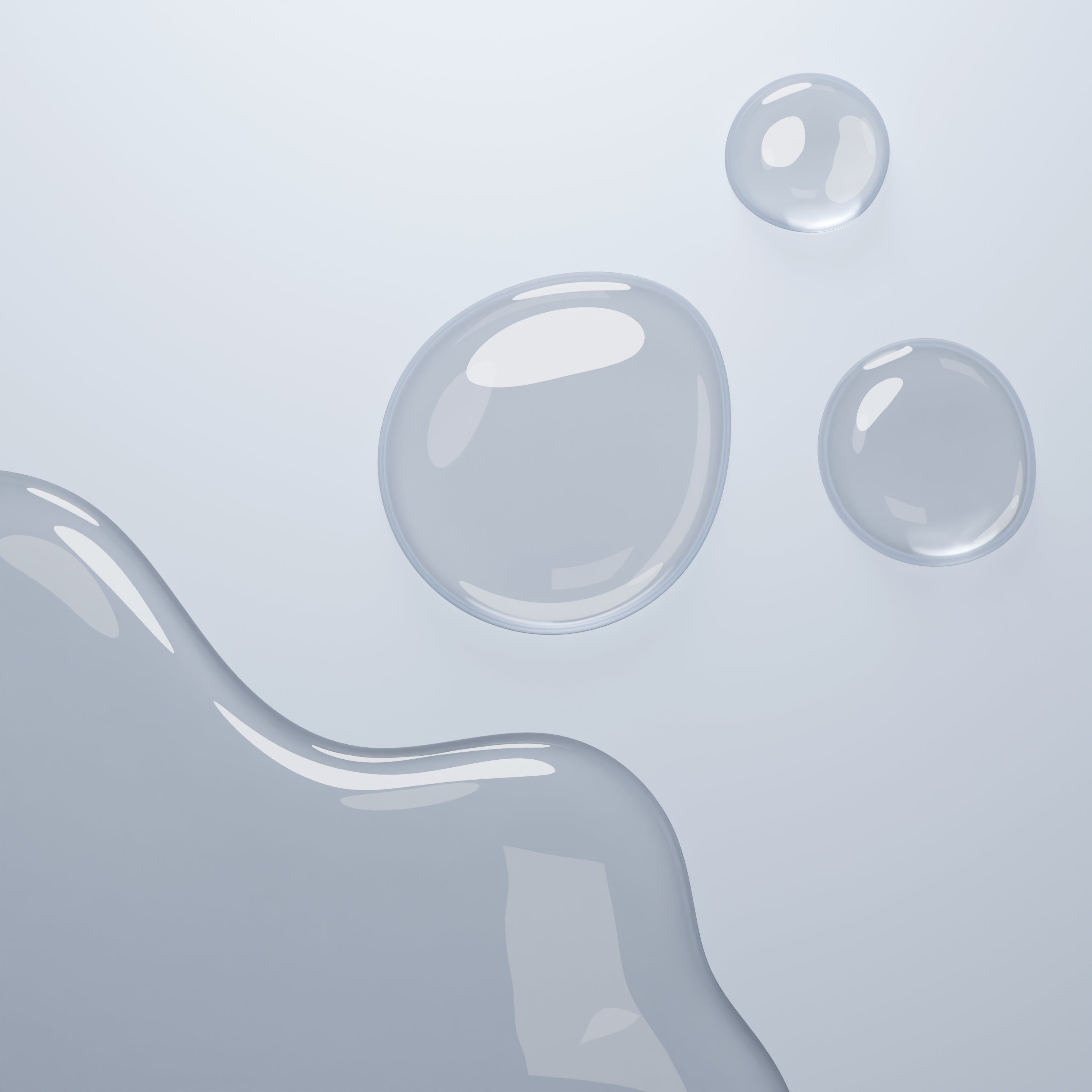 Tre gocce di liquido e una macchia più grande. Il liquido è trasparente e lucido.