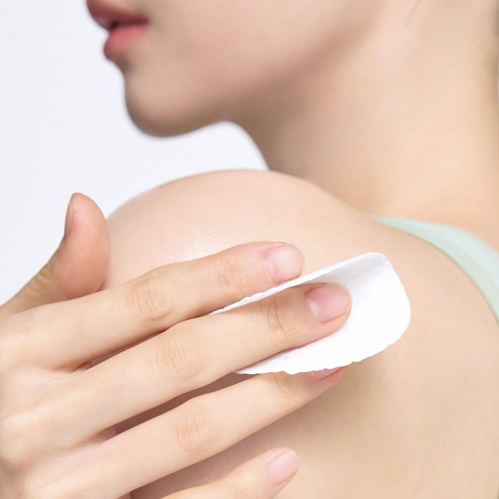 Una mano usa un dischetto illuminante per il corpo CELIMAX Ji Woo Gae sulla spalla.