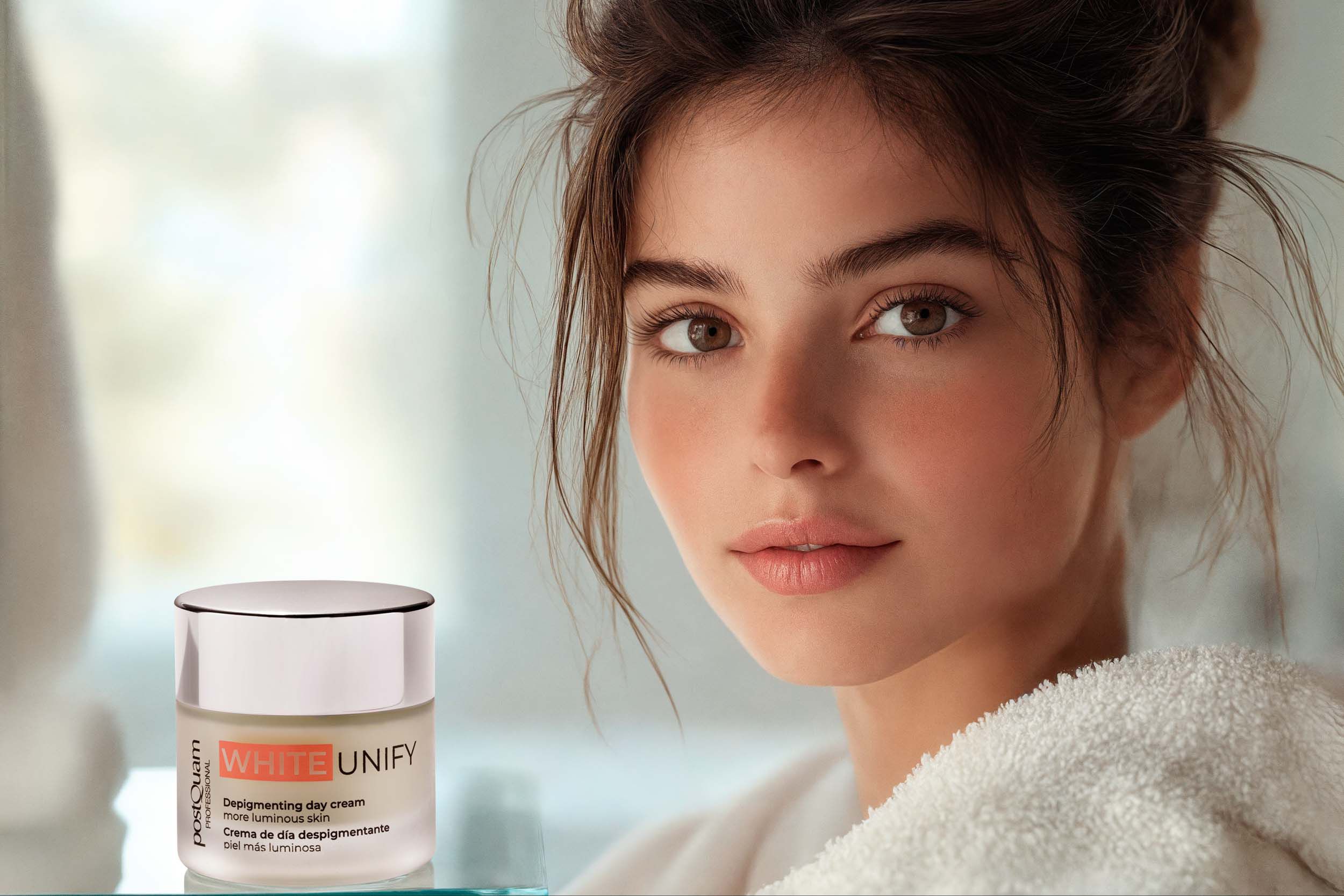 Donna con vaso di crema. Scritta WHITE UNIFY, Depigmenting day cream, pelle più luminosa. Marchio Postquam. Prodotto accanto.