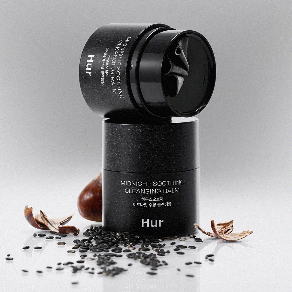 Due barattoli neri sovrapposti. Scritta: Midnight Soothing Cleansing Balm. Marchio: Hur. Sfondo bianco.