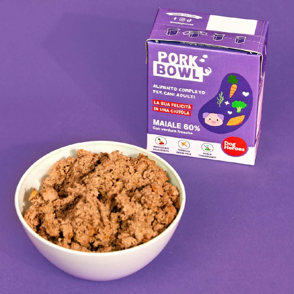 Dog Heroes Pork Bowl in una ciotola. Confezione viola accanto. Cibo con maiale e verdure. Per cani adulti.
