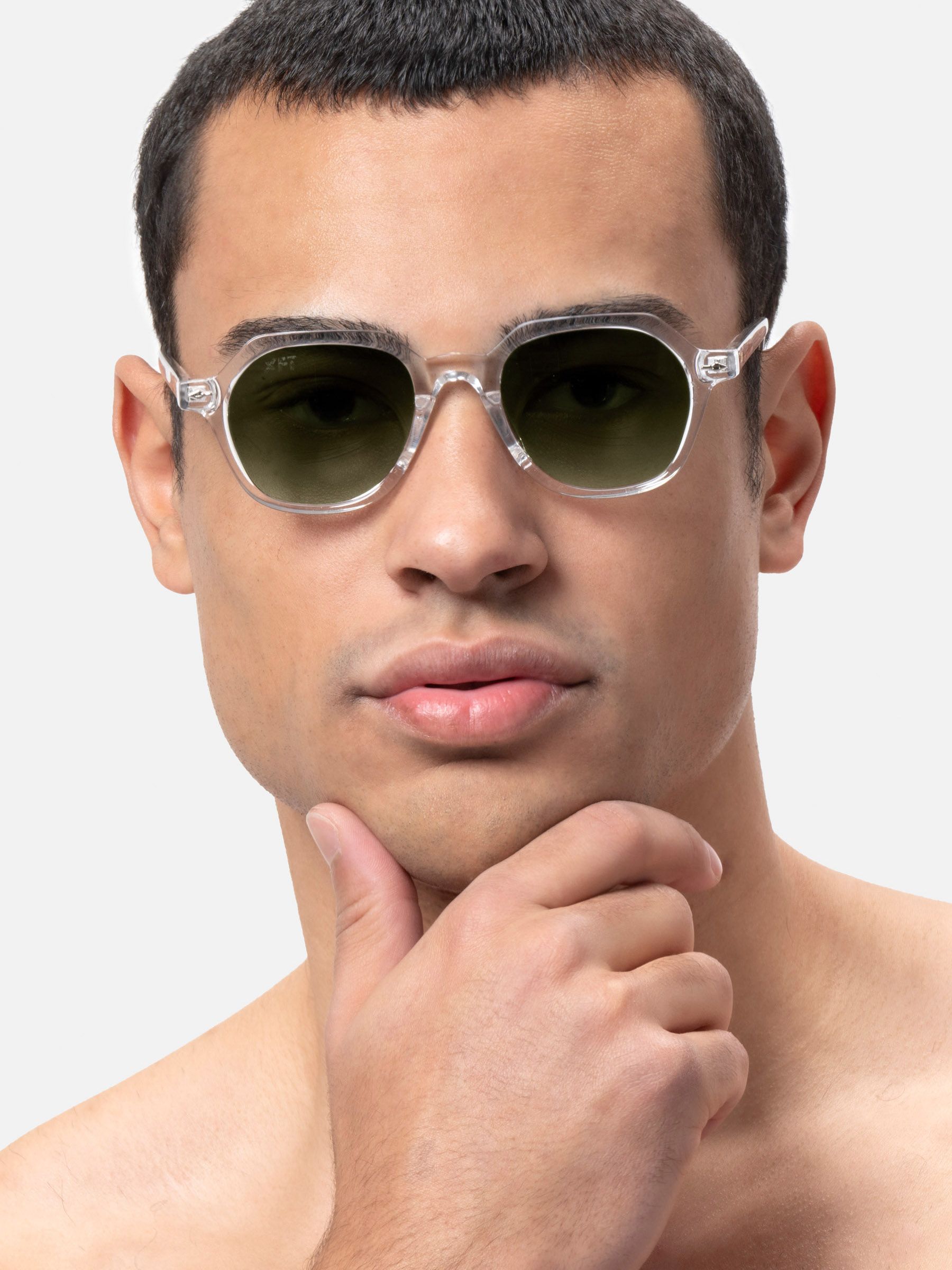 Uomo con occhiali da sole con lenti esagonali e montatura trasparente. Lenti verdi.