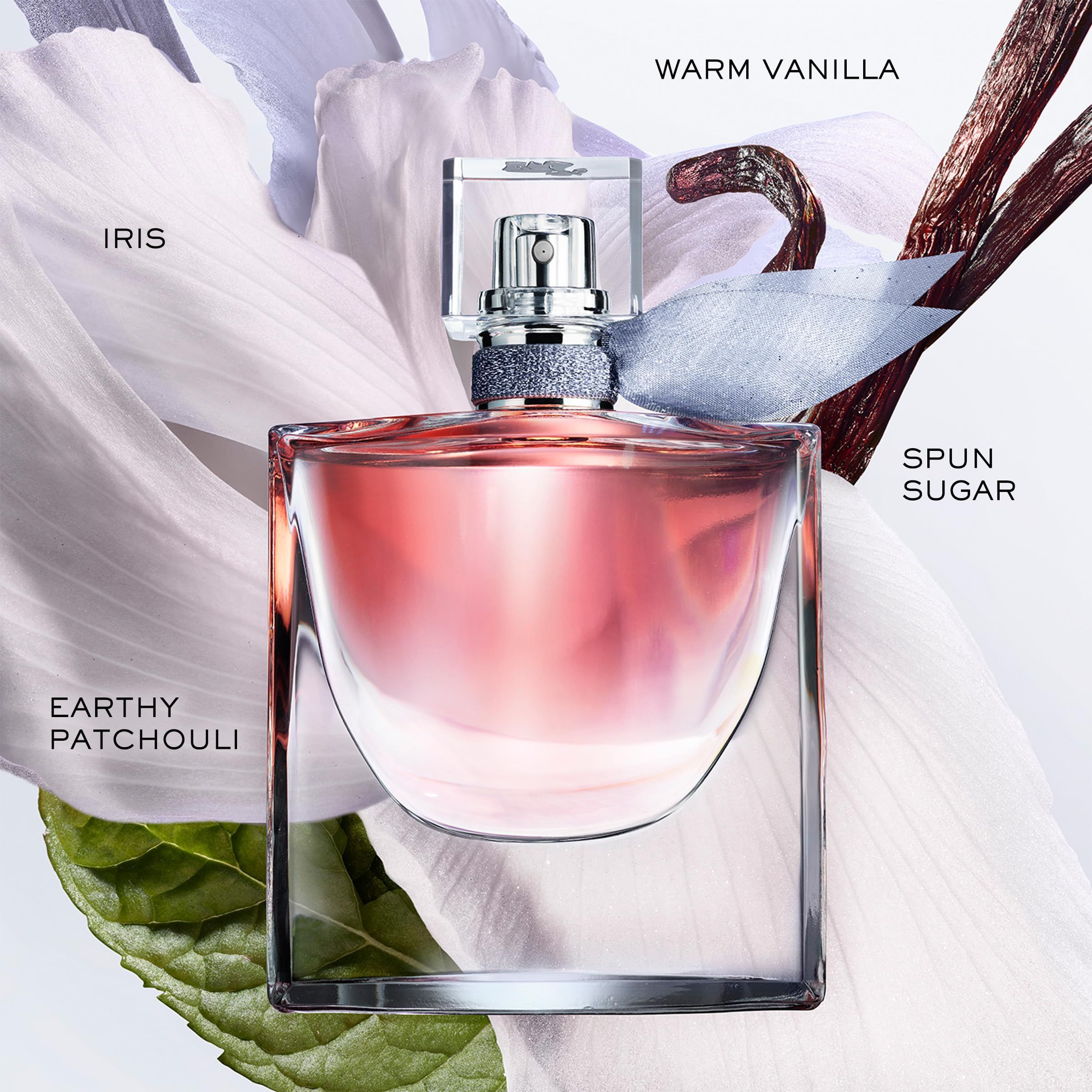 Flacone di profumo con liquido rosa, circondato da petali e ingredienti. Scritta 'La vie est belle'.
