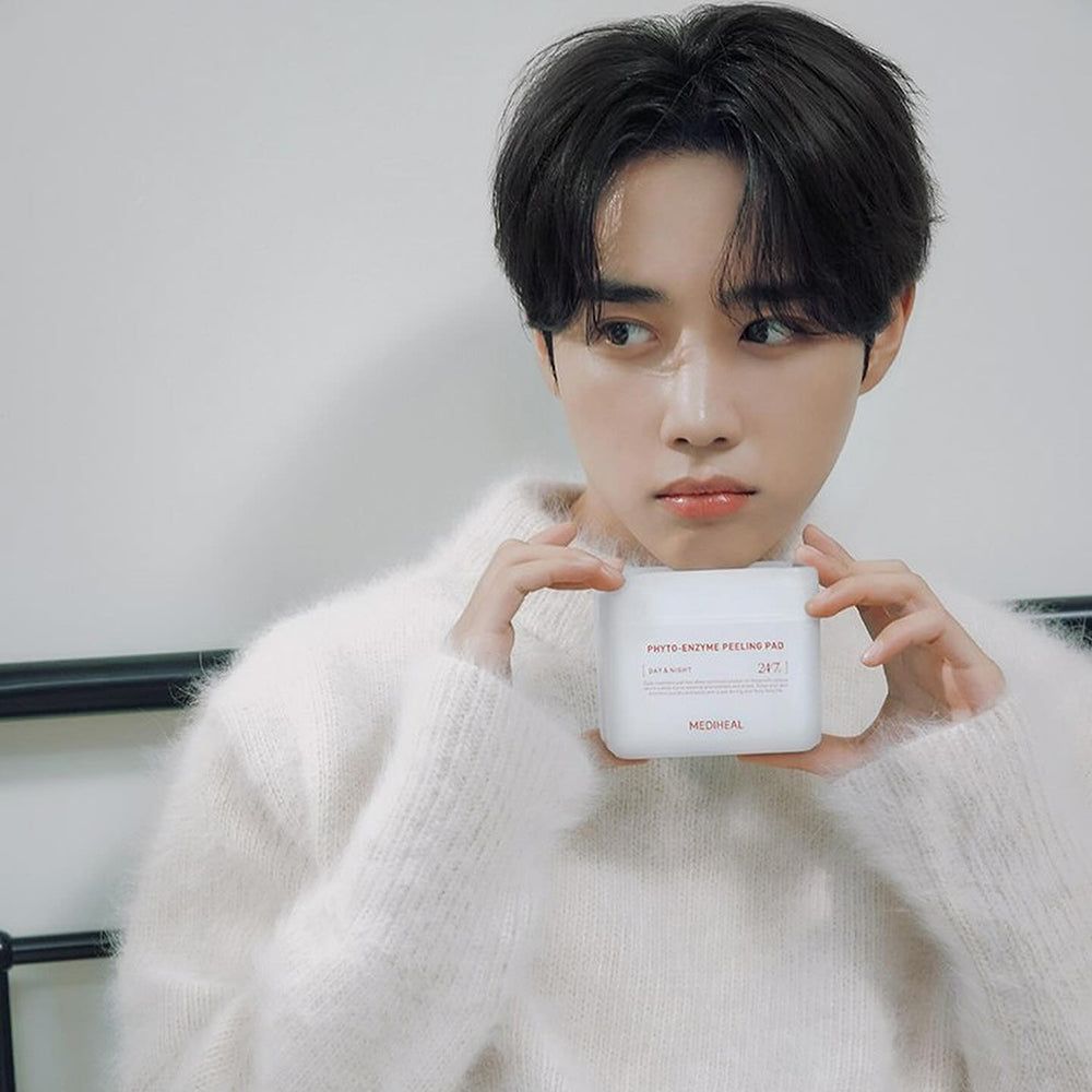 Una persona tiene in mano un contenitore bianco con "PHYTO-ENZYME PEELING PAD" e "MEDIHEAL".