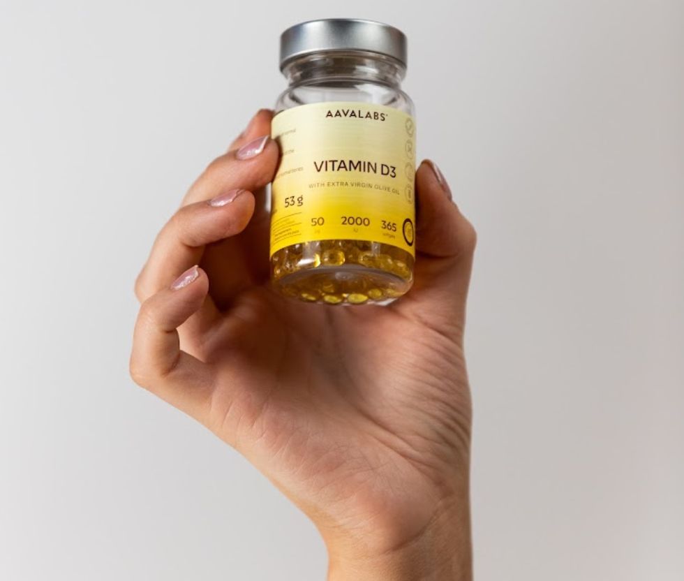 Mano che tiene un flacone Aavalabs Vitamina D3 da 2000 UI, 365 softgel.