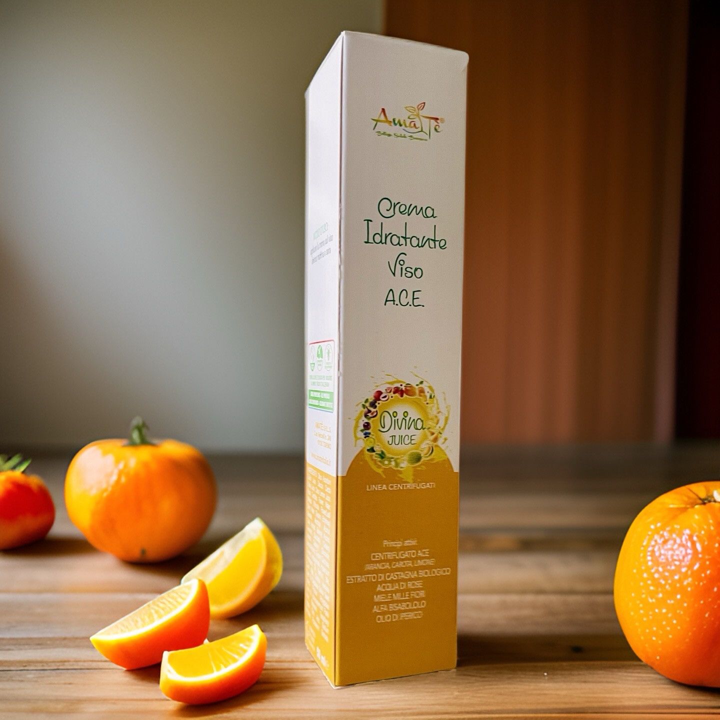 Confezione allungata con nome e logo del prodotto. Scritta: Crema Idratante Viso A.C.E. Divina Juice. Arance e limoni su fondo in legno.