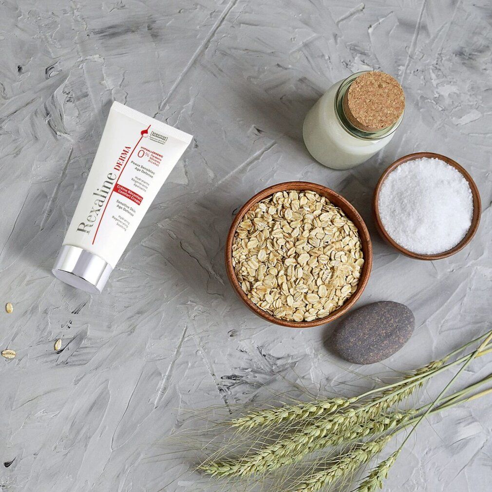 Composizione con tubo di crema, fiocchi d'avena, sale, pietra, barattolo di vetro con tappo e spighe di cereali.