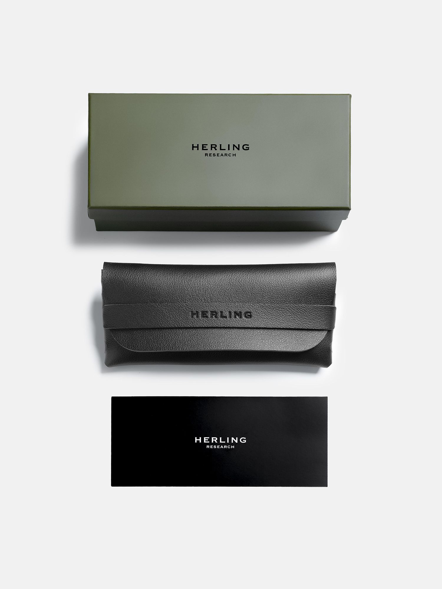 Scatola verde, custodia nera e biglietto nero con la scritta HERLING RESEARCH.