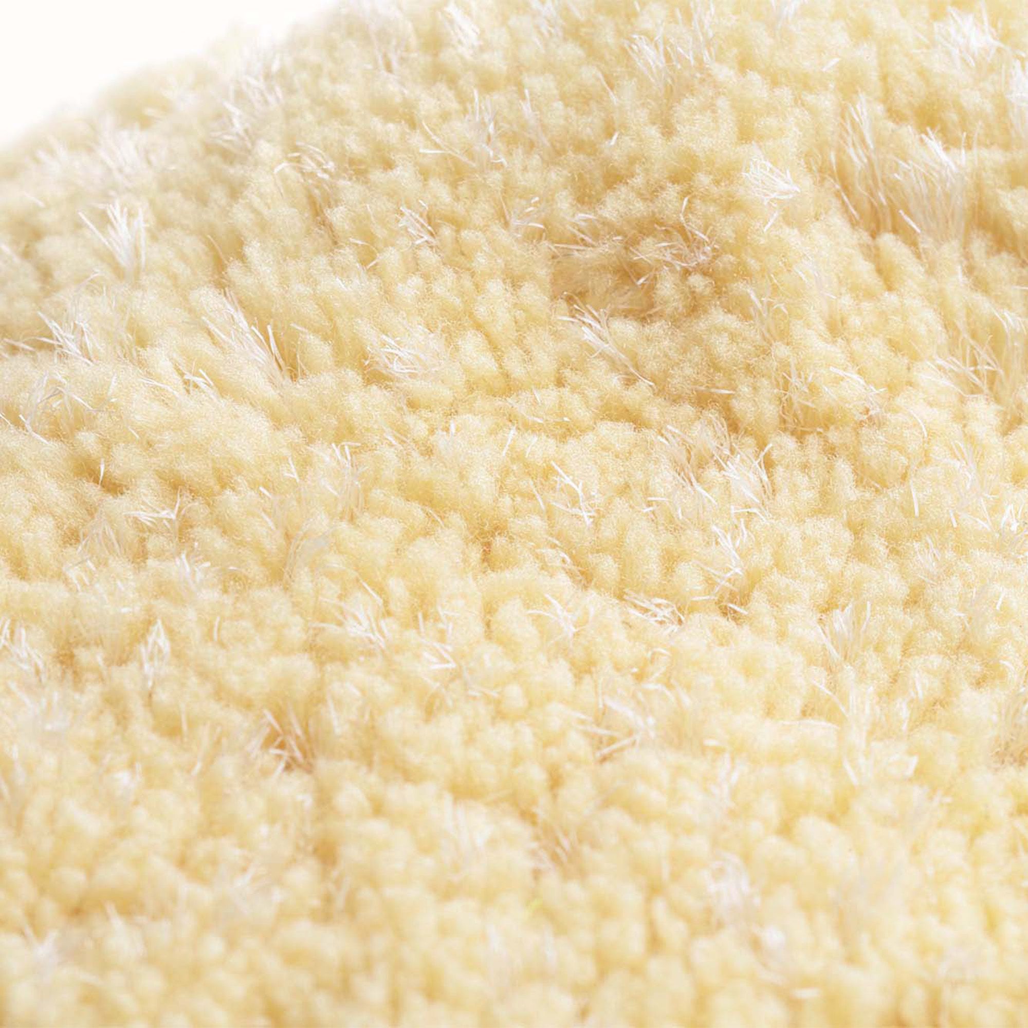 Primo piano di un dischetto struccante ovale giallo. Materiale tessile con struttura visibile.