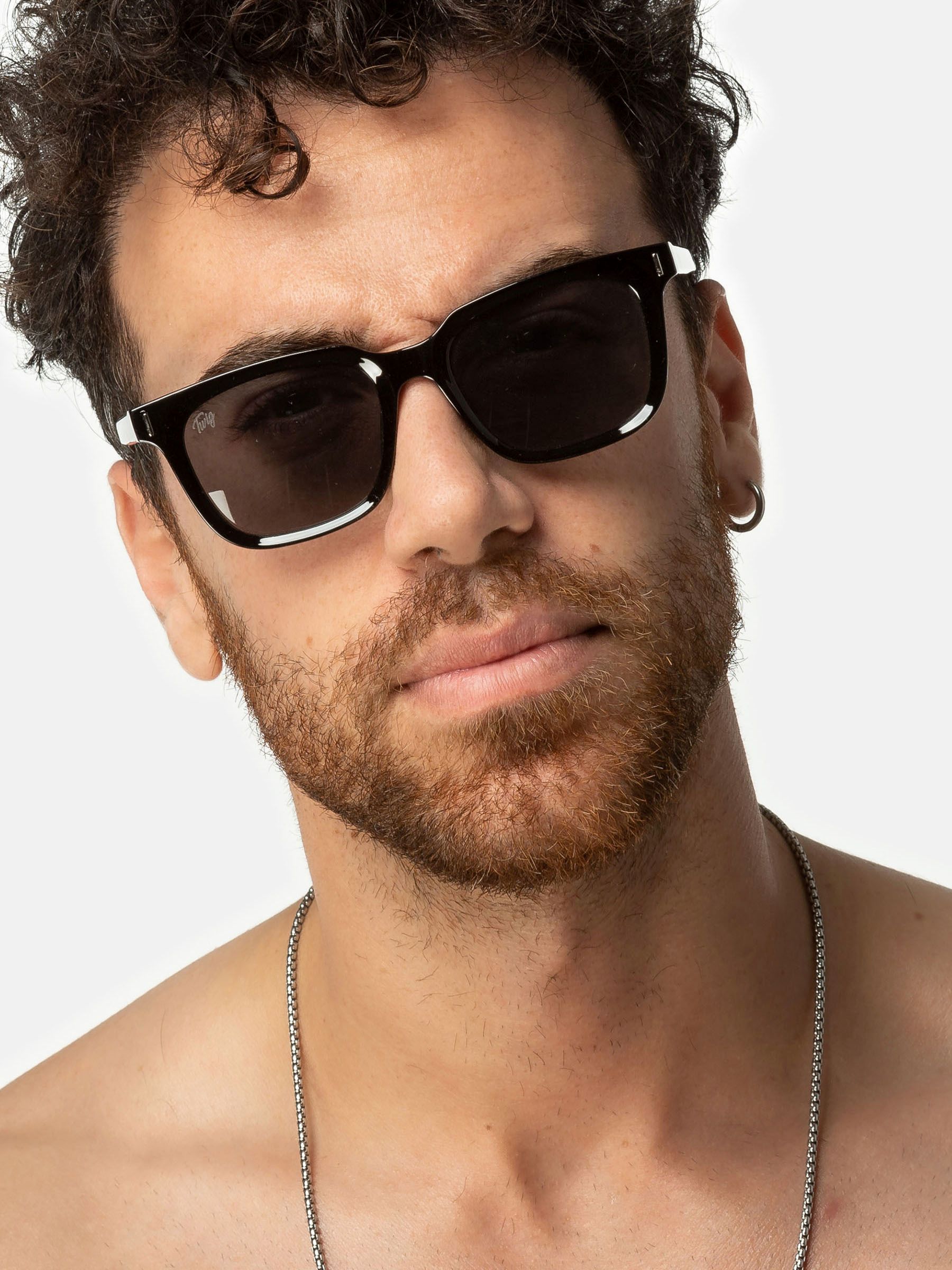 Uomo con occhiali da sole Twig. Montatura nera, lenti rettangolari. Primo piano.