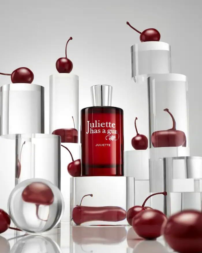 Flacone rosso con ciliegie su piedistalli. Scritta: Juliette has a gun. JULIETTE.