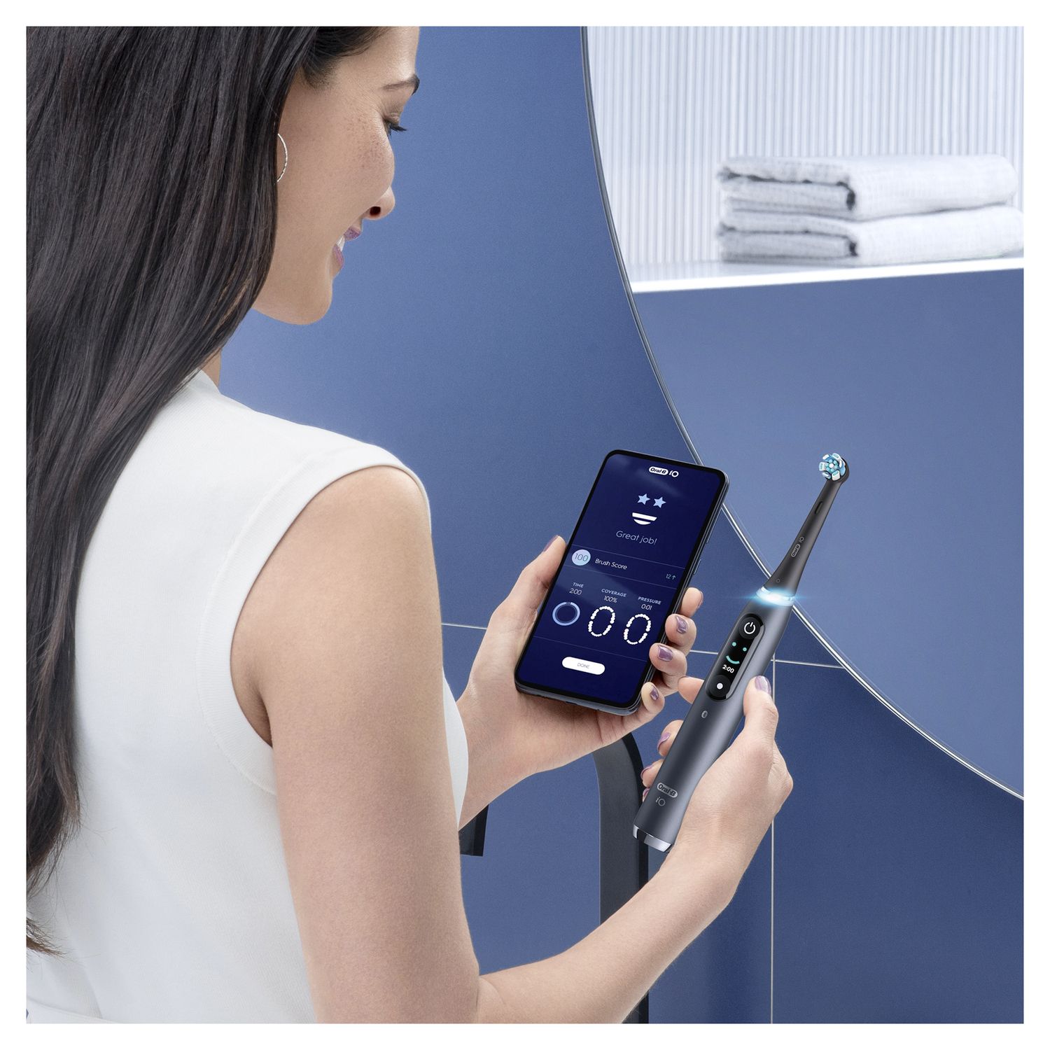 Persona che tiene uno spazzolino elettrico nero e uno smartphone. Visualizzazione dell'app con dati di spazzolatura. Sfondo del bagno.