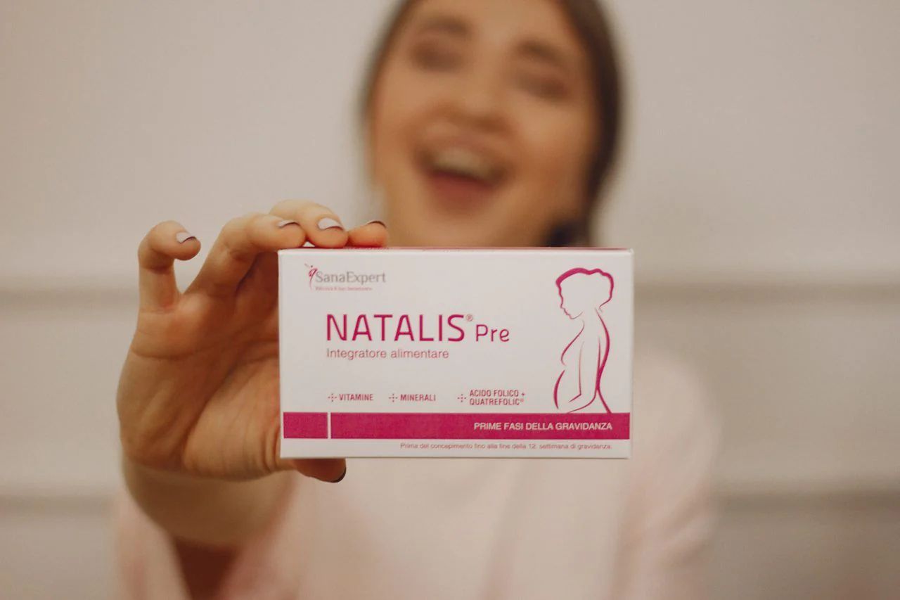 Persona tiene confezione SanaExpert Natalis Pre. Scritta: NATALIS Pre, silhouette donna incinta.