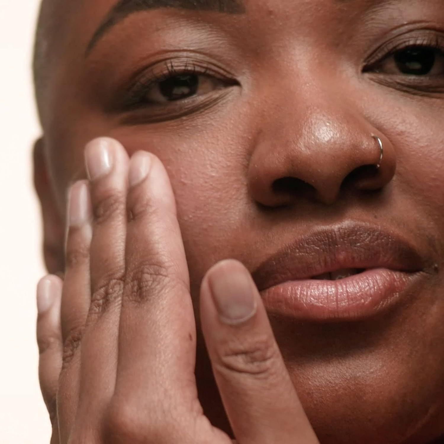 Primo piano di una persona che si tocca la pelle. Focus su viso e mano.