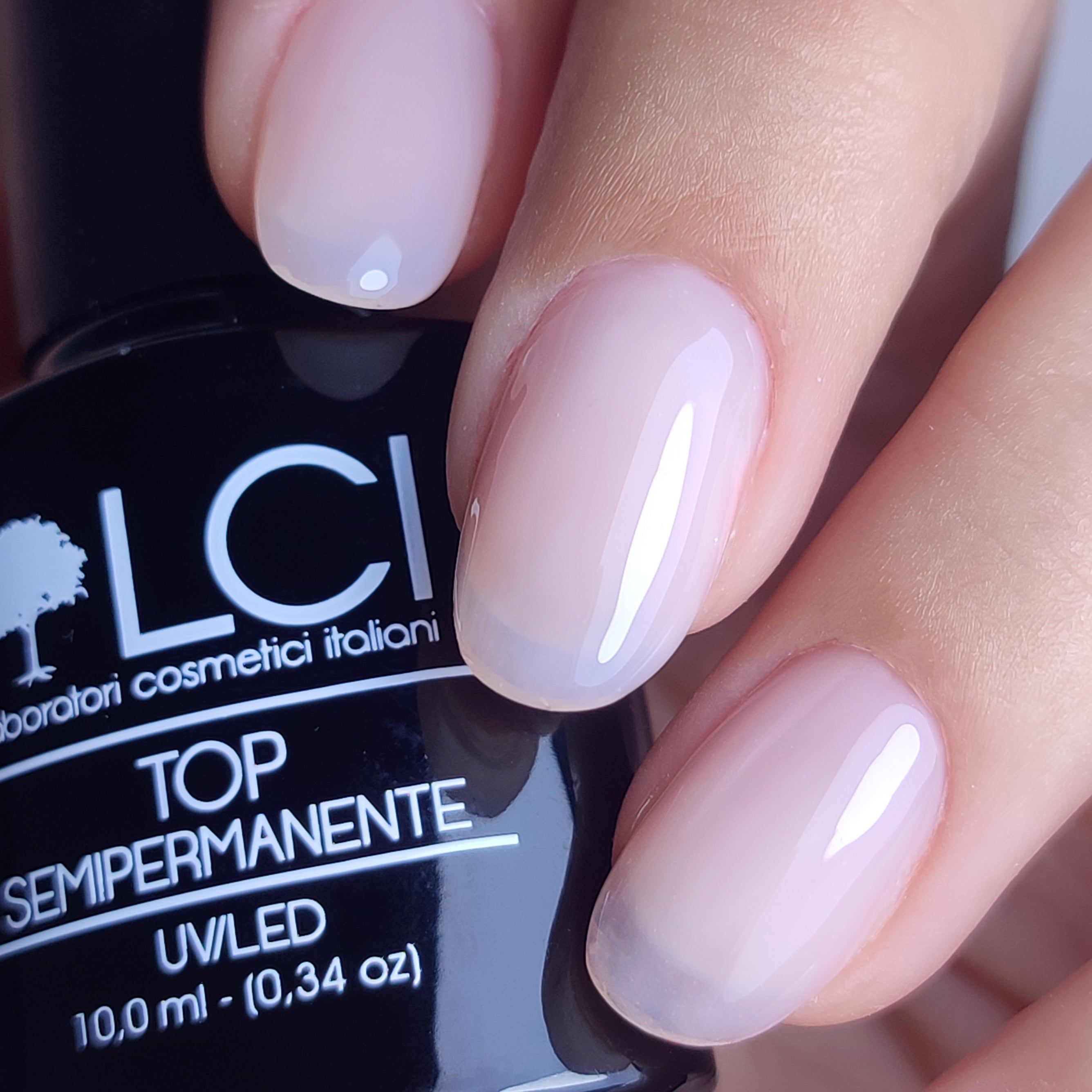 Mano con unghie smaltate. Scritta: LCI, Top Semipermanente, UV/LED. Flacone sullo sfondo.