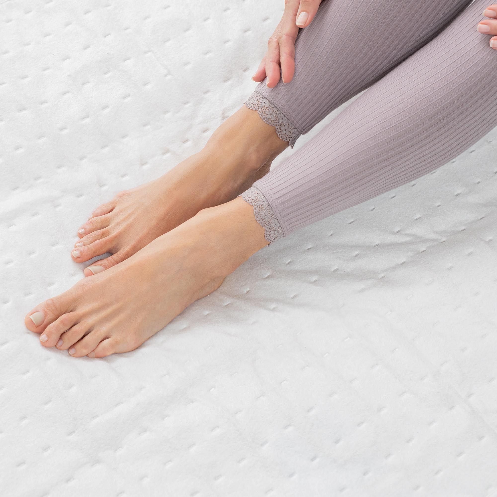 Primo piano di piedi su un sottocoperta termico bianco. La persona indossa leggings.