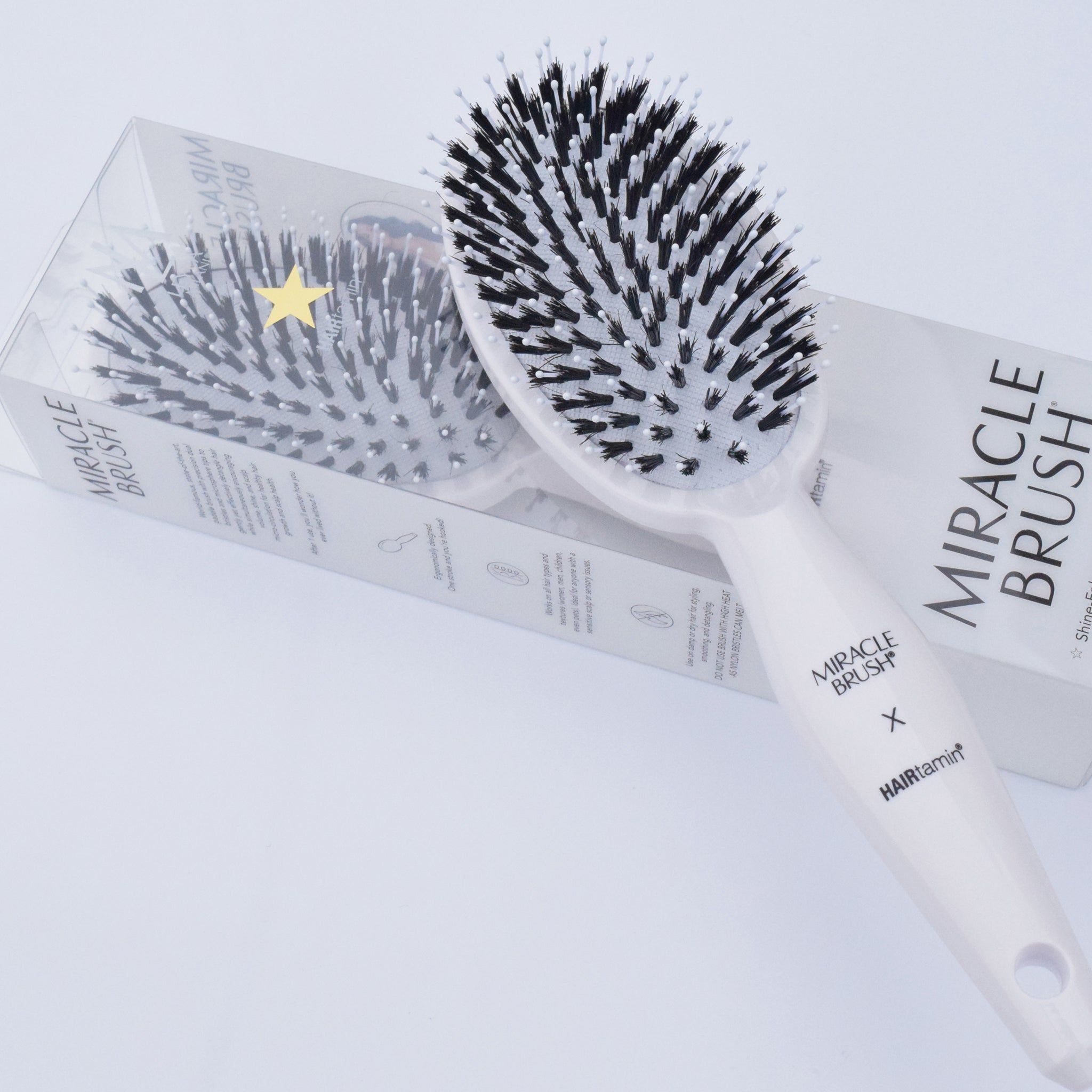 Spazzola bianca con setole nere nella confezione. Scritta MIRACLE BRUSH X HAIRtamin.