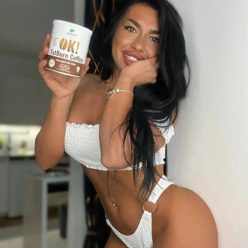 Una donna tiene una lattina OK! FatBurn Coffee, sorridendo alla telecamera.