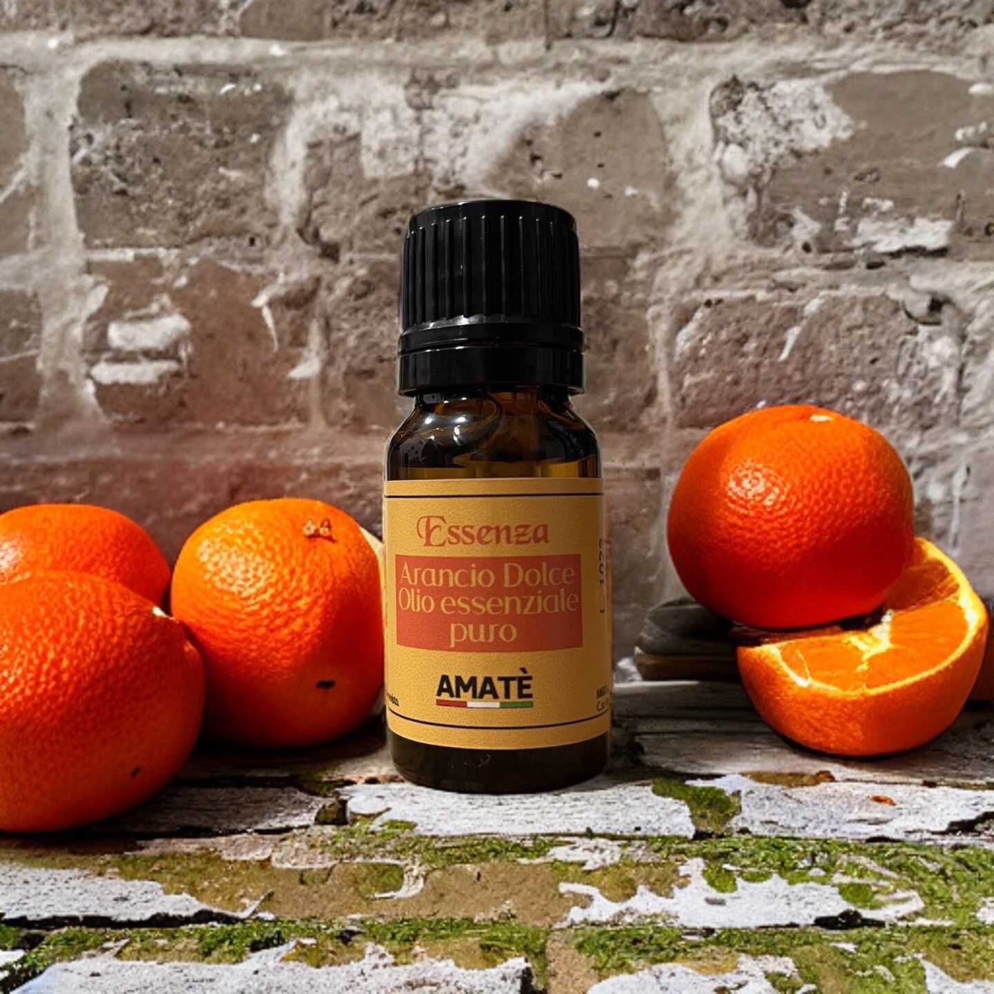 Flacone di vetro marrone con tappo nero, accanto ad arance. Etichetta con testo: Arancio Dolce, Olio essenziale puro, AMATÈ.