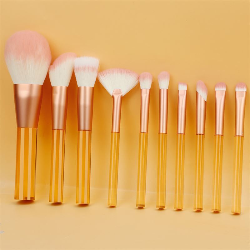 Set di pennelli per trucco con manici arancioni trasparenti e setole rosa. Varie forme e dimensioni.