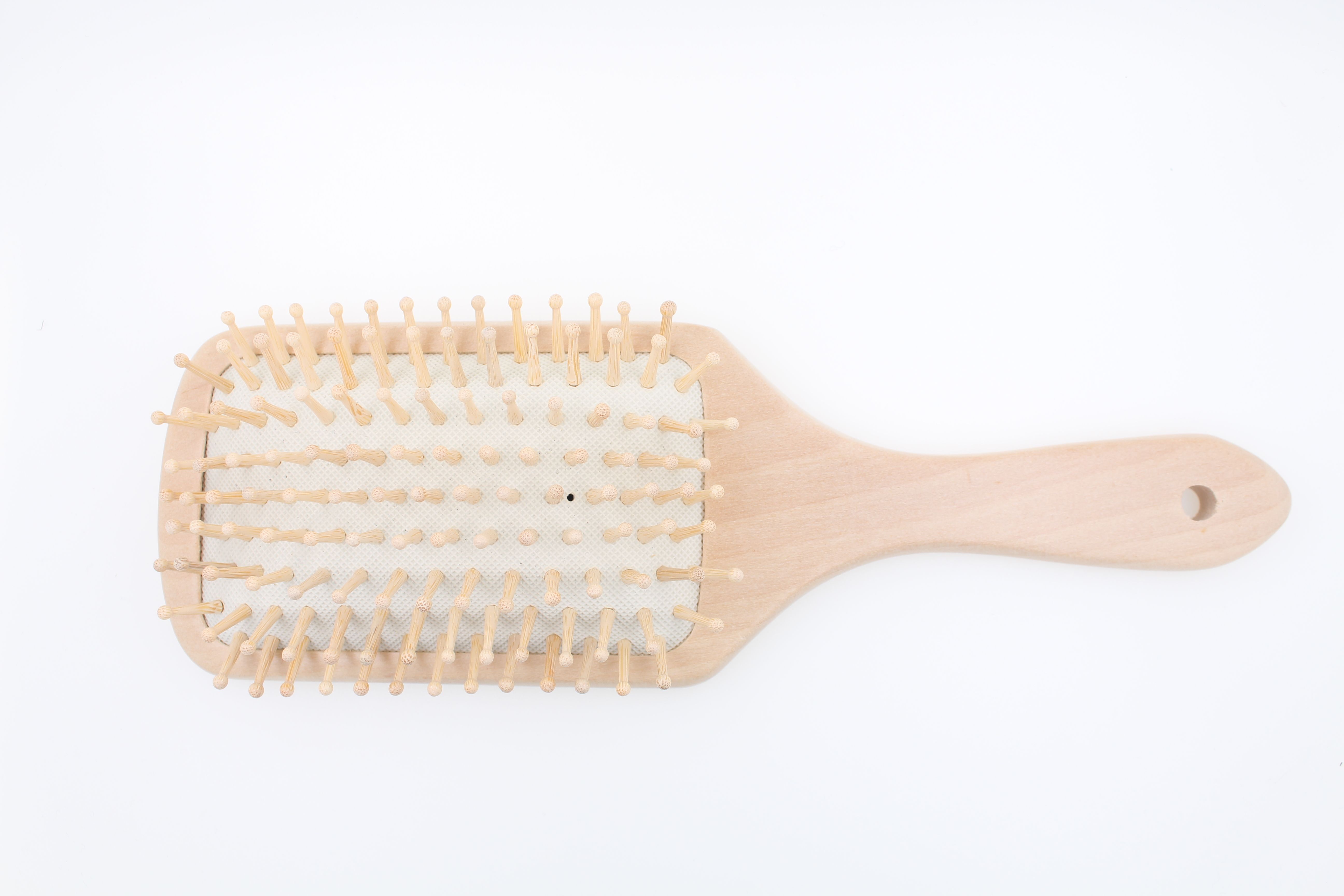 Spazzola per capelli in legno con testa rettangolare e angoli arrotondati, dotata di molti denti in legno.