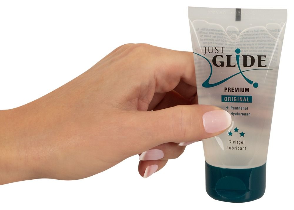 Mano che tiene un tubo trasparente con tappo blu. Scritta: Just Glide, Premium Original, Panthenol, Hyaluronan. Lubrificante.