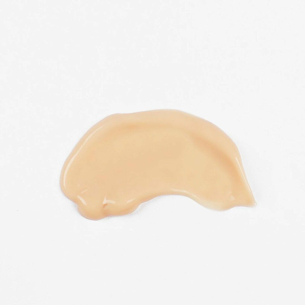 Macchia di crema chiara su sfondo bianco. Forma irregolare, allungata.