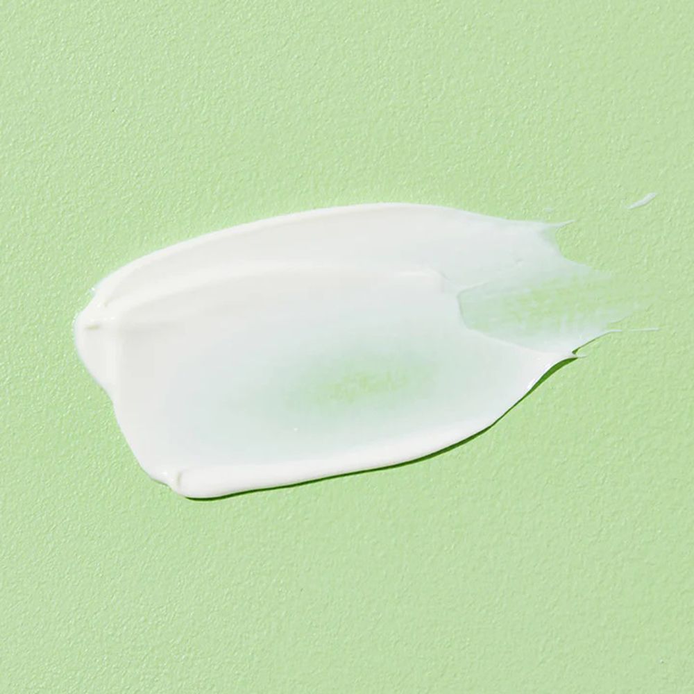 Macchia di crema bianca su sfondo verde. Consistenza visibile.