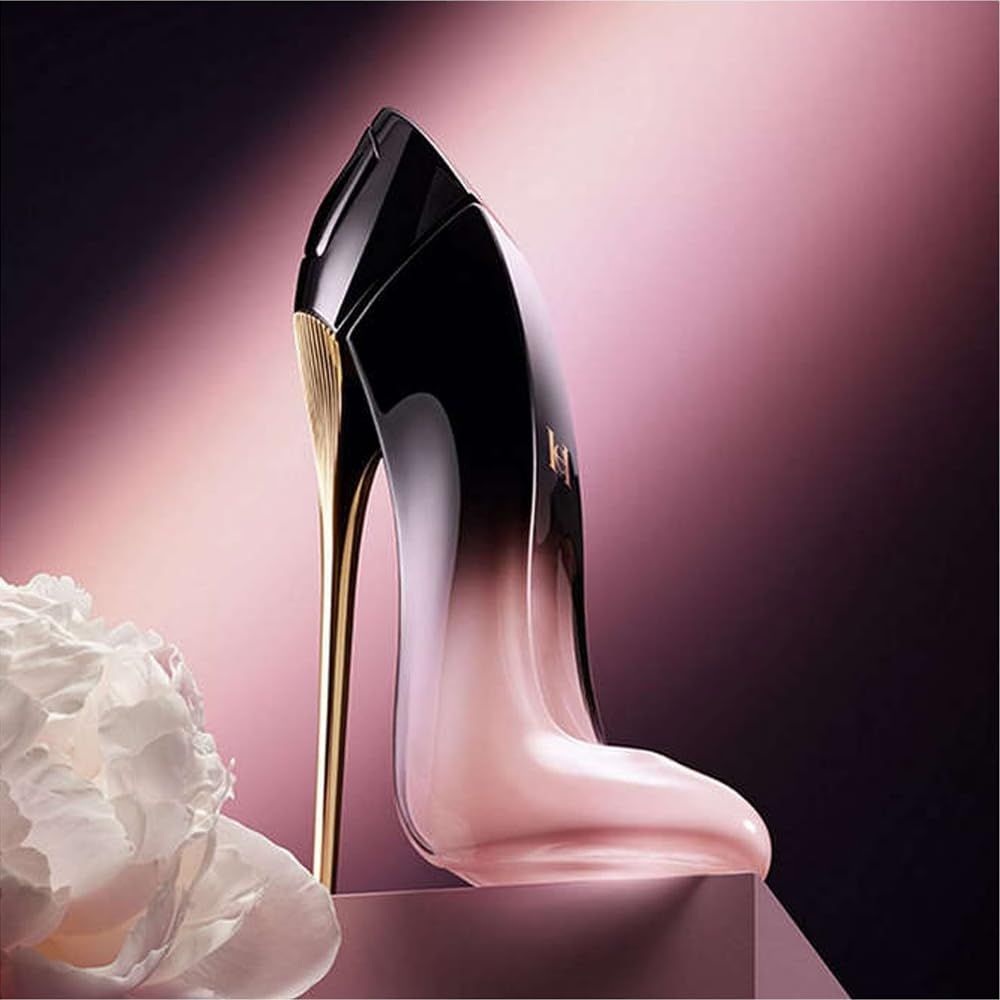 Flacone di profumo a forma di scarpa. Sfumatura nero-rosa, tacco dorato. Posizionato su piedistallo, sfondo rosa.