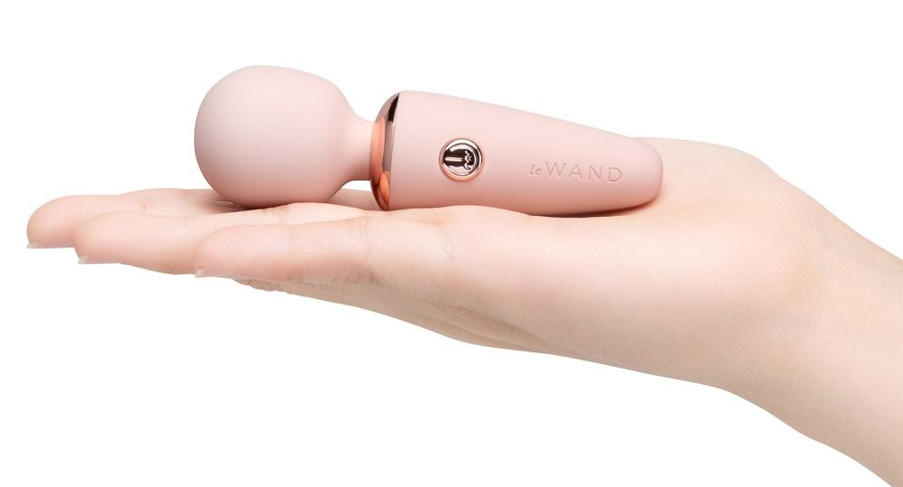 Un piccolo vibratore rosa con testa sferica e manico conico, tenuto in una mano.
