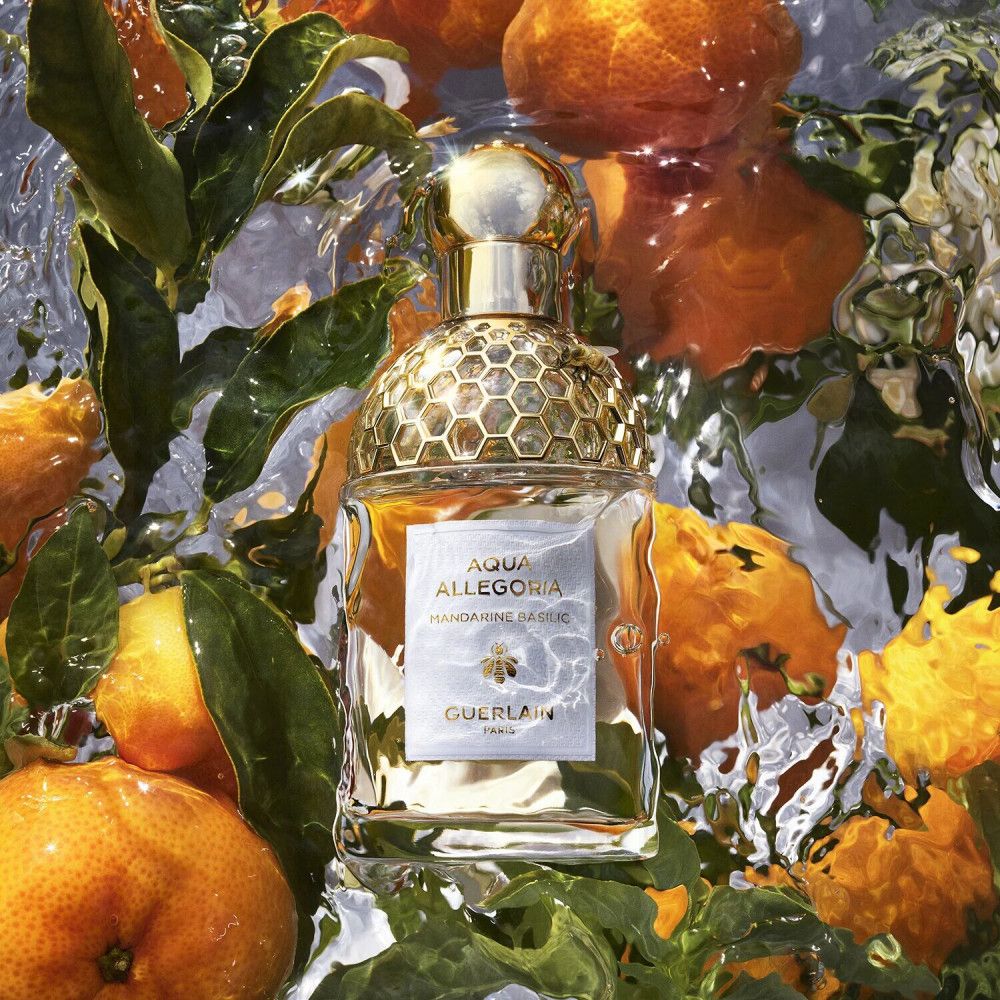 Flacone di profumo in acqua con mandarini e foglie. Scritta: Aqua Allegoria Mandarine Basilic, Guerlain.