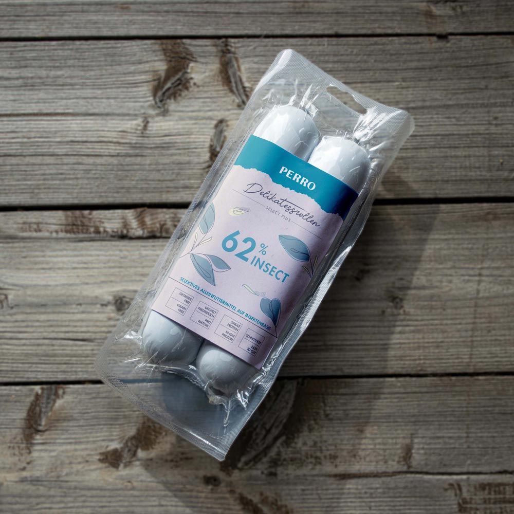 Confezione con due salsicce. Scritta: PERRO Delikatessrolle INSECT, 62% INSECT. Su sfondo legno.