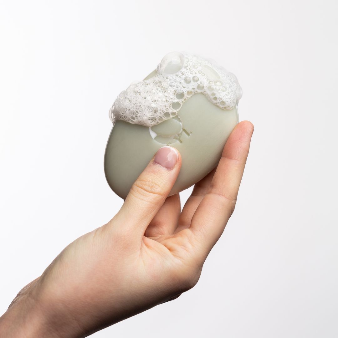 Sapone ovale in mano, ricoperto di schiuma.